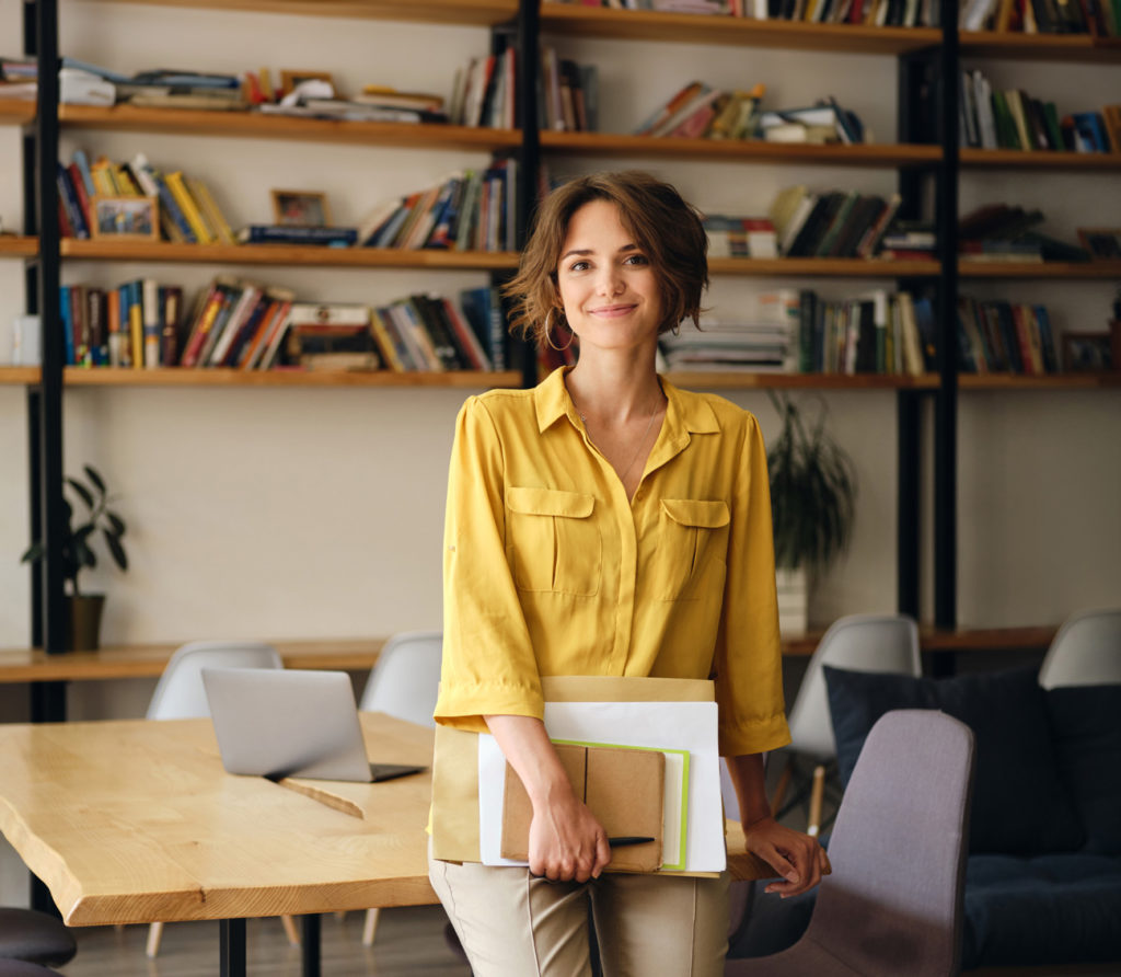 Woman in a yellow shirt holding notebooks